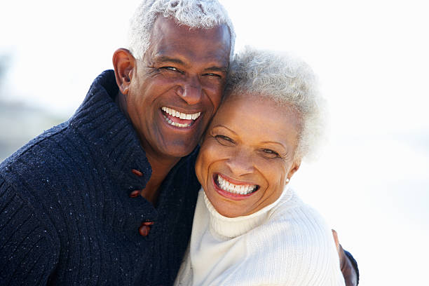 Romantic Senior Couple Hugging On Beach Smiling To Camera