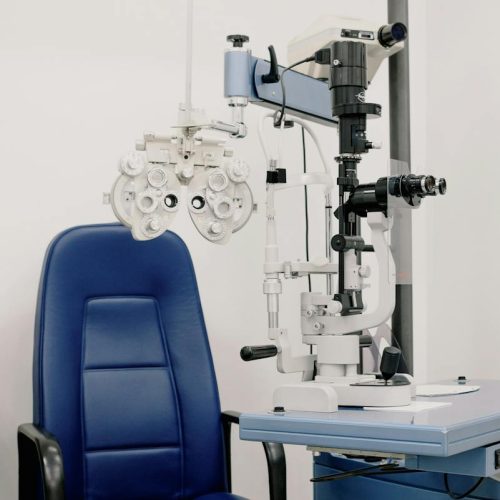 Interior of modern medical office equipped with chair and phoropter for treatment and checking eyesight